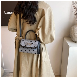 Detailed back view of a grey polka dot handbag with a golden bow buckle on a model
