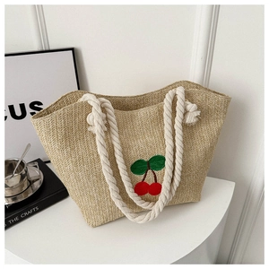 Détail du sac cabas en paille tissée avec broderie cerise rouge et anses en corde de coton