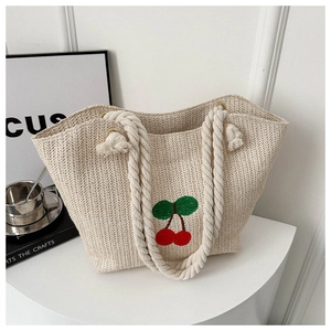 Détail du sac cabas en paille beige avec broderie cerise rouge et poignées en corde