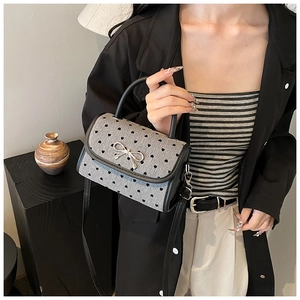 Detailed close-up of a grey mini handbag featuring black heart patterns and silver bow clasp
