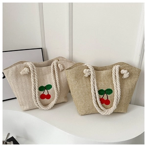 Détail de sacs fourre-tout en paille tressée avec broderie cerise et anses en coton