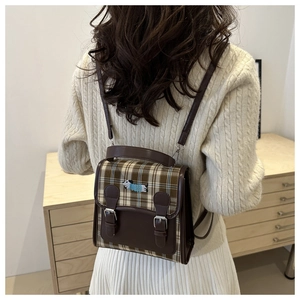 Detail of dog embroidery and vintage leather buckles on a brown plaid backpack