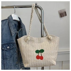 Détail du sac cabas en paille d'été avec cerises brodées et anses en corde de coton blanc