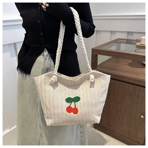 Détail du sac cabas en paille beige avec broderie cerise rouge et anses en corde de coton