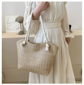 Straw tote bag with cotton rope handles and herringbone weave texture on a model