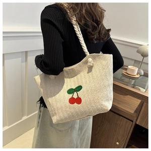 Détail du sac cabas en paille tissé avec broderie cerise et poignée en corde