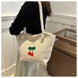 Détail du sac cabas en paille tissée avec motifs de cerises brodés et anses en corde