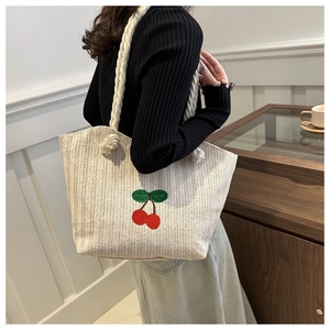 Détail du sac cabas en paille tissée avec broderie cerise et anses en corde de coton