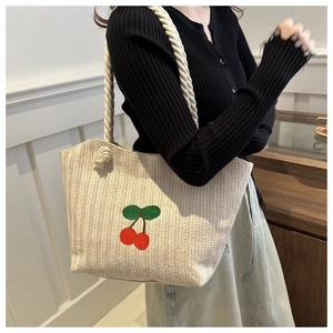 Détail d'un sac cabas en paille avec broderie cerise et anses en corde de coton