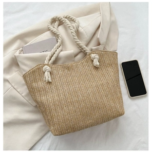 Detail of woven straw tote bag with white cotton rope handles and rustic knot design