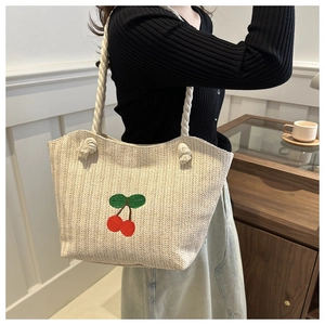 Détail du sac en paille avec broderie de cerises rouges et anses en corde de coton