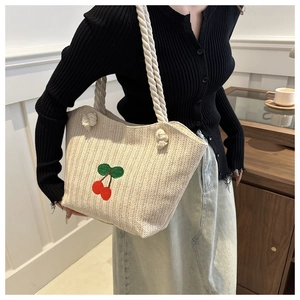 Détail du sac cabas en paille tressée avec cerises brodées et anse en corde de coton épais