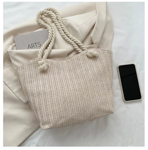 Close-up of woven straw tote bag featuring herringbone texture and sturdy rope handles