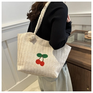 Détail du sac cabas en paille beige avec broderie cerise rouge et anses en corde de coton