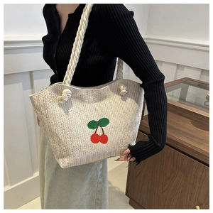 Détail du sac cabas en paille avec broderie cerise et anses en corde de coton