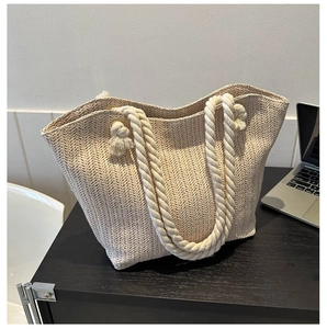 Detail of beige straw tote bag featuring V-shaped woven texture and cotton rope handle