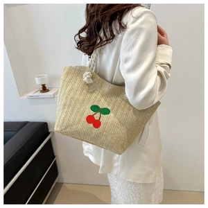 Détail du sac cabas en paille tissée avec broderie cerise rouge et lanières en corde de coton