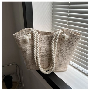 Detail of hand-woven straw tote bag with braided texture and thick cotton rope handles