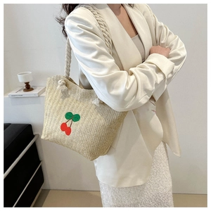 Détail du sac cabas en paille tissée avec broderie cerise rouge et anses en corde