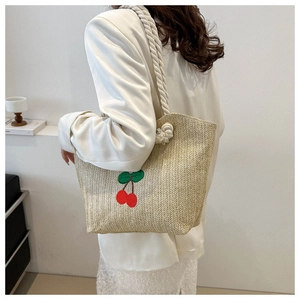 Détail du sac cabas en paille tissée avec broderie cerise rouge et anse en corde de coton