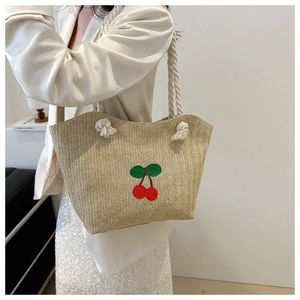 Détail d'un sac cabas en paille avec broderie cerises rouges et poignée en corde blanche