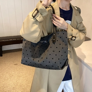 Polka dot tote bag with silver bow detail and black straps shown on a model