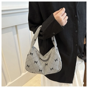 Detail of gray corduroy underarm bag featuring quilted diamond pattern and black bow print