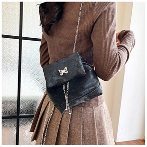 Detail of a black velvet mini backpack with a silver butterfly clasp on a female model