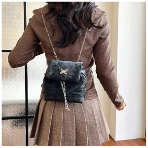 Close-up of black velvet mini backpack featuring silver bow hardware and fringe detail