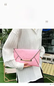 Pochette enveloppe rose avec motif étoiles et boucle en métal doré sur un mannequin