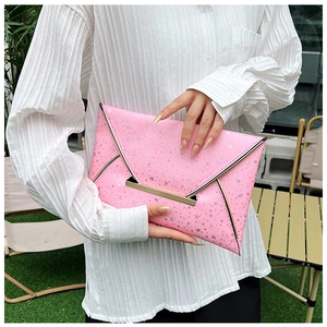 Détail de la pochette enveloppe rose avec étoiles argentées et bordure dorée chic