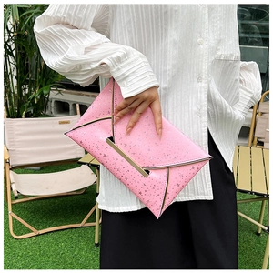 Détail de pochette enveloppe rose avec motifs d'étoiles et bordure en métal doré
