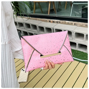 Détail d'une pochette enveloppe rose avec motifs d'étoiles argentées et boucle dorée