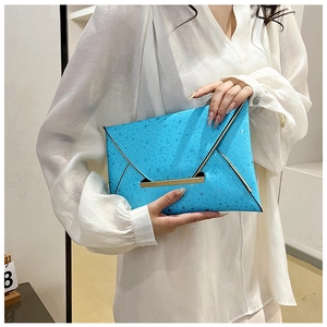 Détail d'une pochette enveloppe bleu vif avec motifs d'étoiles et barre en métal doré
