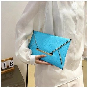Détail d'une pochette enveloppe bleu clair avec motifs étoiles et finitions métalliques dorées
