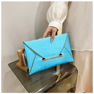 Détail de la pochette enveloppe bleu brillant avec motifs d'étoiles et fermoir doré