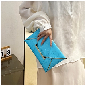 Gros plan sur pochette enveloppe bleu vif avec motifs d'étoiles argentées et barre dorée
