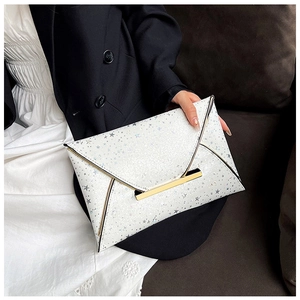 Détail de la pochette enveloppe à paillettes argentées avec motifs d'étoiles et boucle d'or