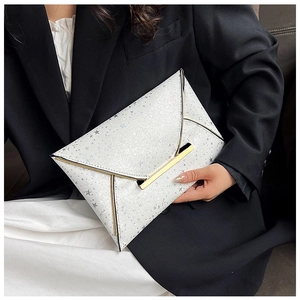 Détail d'une pochette enveloppe blanche à paillettes étoiles argentées et bord doré