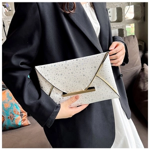Détail de la pochette enveloppe blanche avec étoiles argentées et bordure dorée en métal