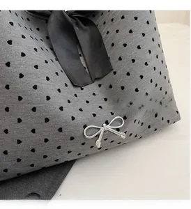 Detail of silver bow hardware and heart polka dot pattern on canvas tote bag