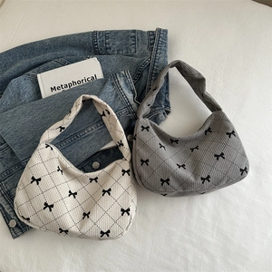 Quilted corduroy shoulder bags with black bow accents in cream and dark gray colors