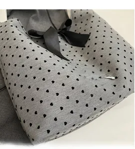 Close-up of grey knit fabric featuring black heart patterns and a satin bow detail