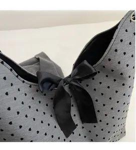 Close-up of grey polka dot tote with heart prints and a black satin bow detail