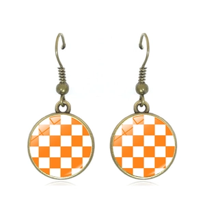 Macro view of checkered copper drop earrings with orange and white grid patterns