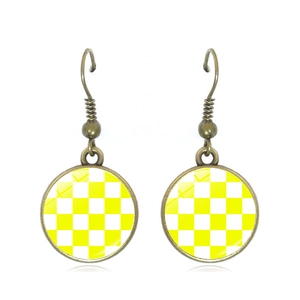 Detail of vintage bronze hoop earrings with yellow and white checkerboard glass dome charm