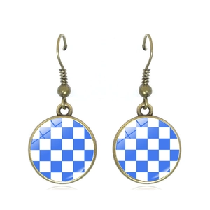 Detail of vintage bronze hook earrings with blue and white checkerboard pattern charm