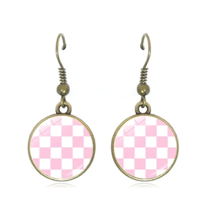 Close-up of vintage bronze drop earrings with pink and white checkered pattern inlay