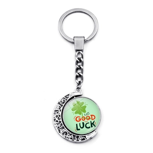 Detail showing the rotating green four-leaf clover pendant on a silver keychain with moon motif