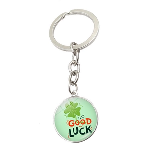 Detailed view of silver metal keychain with green four-leaf clover and Good Luck text